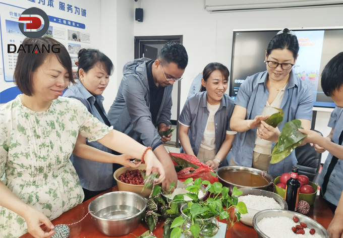 Datang Finned Tube employees collaborating and laughing while preparing rice dumplings for the company Dragon Boat Festival celebration